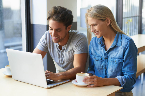 Relajándose en el café. una pareja joven usando un ordenador portátil en un café - Foto, Imagen