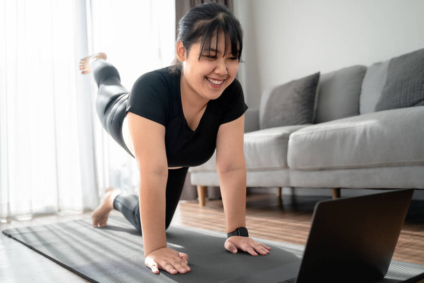 Asiatico paffuto donna in salotto pratica lezione di yoga online con il computer. femminile che ha meditato la classe di formazione sul computer portatile. - Foto, immagini