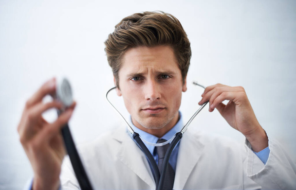 Může se vyskytnout nesrovnalost... seriózně vyhlížející doktor drží konec stetoskopu směrem ke kameře - Fotografie, Obrázek