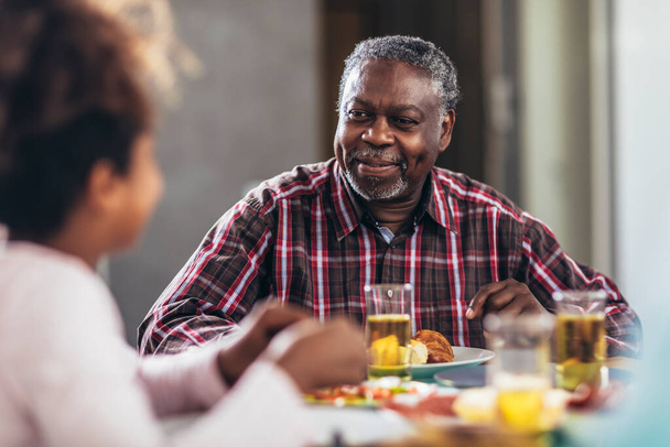 Una famiglia afro-americana multigenerazionale che si gode il cibo a tavola. - Foto, immagini