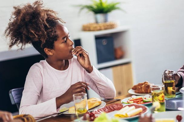 Eine afroamerikanische Mehrgenerationenfamilie genießt das Essen am Esstisch. - Foto, Bild