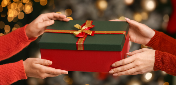 Vrouw geeft cadeau aan haar vriend op kerstavond, close-up - Foto, afbeelding