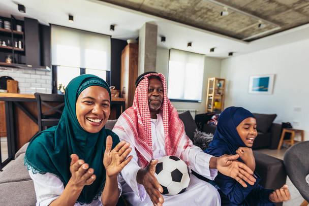 Арабський чоловік дивиться телевізор вдома під час спортивного заходу зі своєю сім'єю. Дивитися футбол. - Фото, зображення