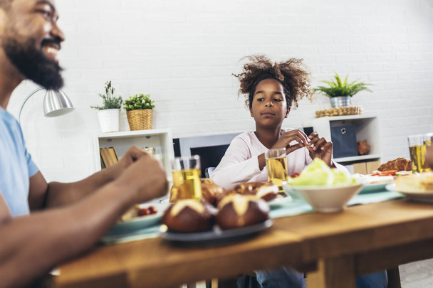 Una familia afroamericana multigeneracional disfrutando de la comida en su mesa. - Foto, Imagen