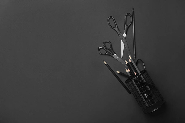 Paperitarvikkeiden, saksien ja lyijykynien kumottu haltija mustalla pohjalla - Valokuva, kuva