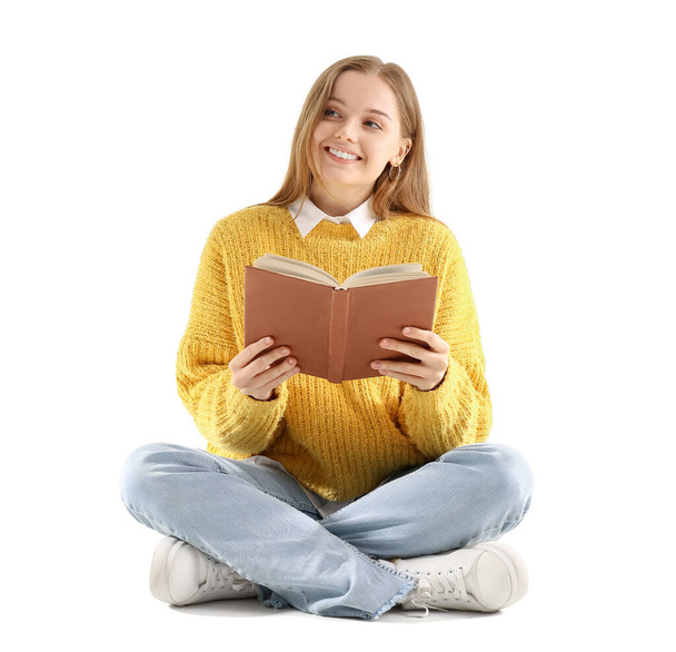 Молода жінка в жовтому светрі з книгою, що сидить на білому тлі
 - Фото, зображення