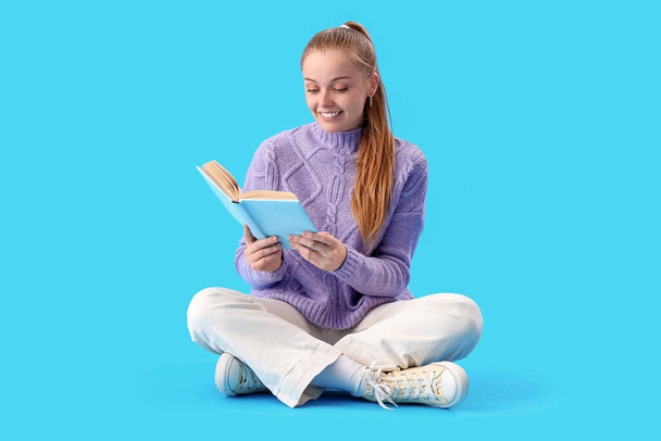 Молодая женщина читает книгу на синем фоне - Фото, изображение