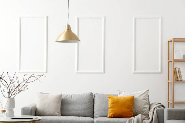 Acogedor sofá con cojines y cuadros en el interior de la sala de estar de luz - Foto, Imagen