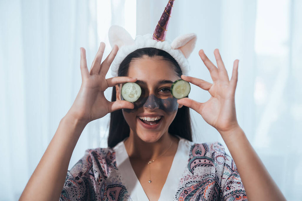 Funny sonriente Spa Mujer con Máscara Facial fresca mantenga los pepinos. Hermosa mujer aplicando máscara facial casera natural - Foto, Imagen