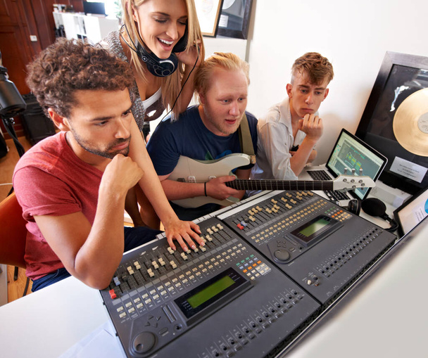 Давайте послушаем... четыре молодых музыкальных продюсера сидят перед микшерским столом в своей студии - Фото, изображение