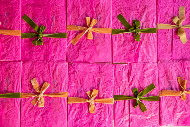 Sobres rosados decorados con cintas de colores y arcos se apilan juntos en la mesa, vista superior. Imagen de fondo sobre un tema de saludo y vacaciones - Foto, imagen