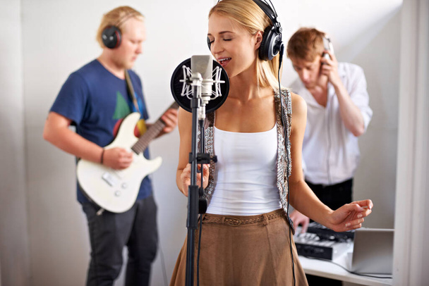 Making musical history. A band consisting of three young adults busy recording a track - Fotoğraf, Görsel