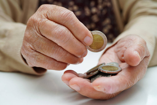 Retired elderly woman counting coins money and worry about monthly expenses and treatment fee payment. - Foto, imagen
