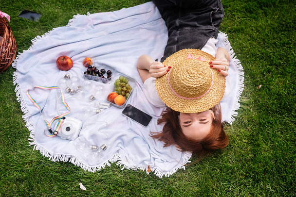 Giovane donna felice sdraiata su una coperta sul prato del parco. - Foto, immagini