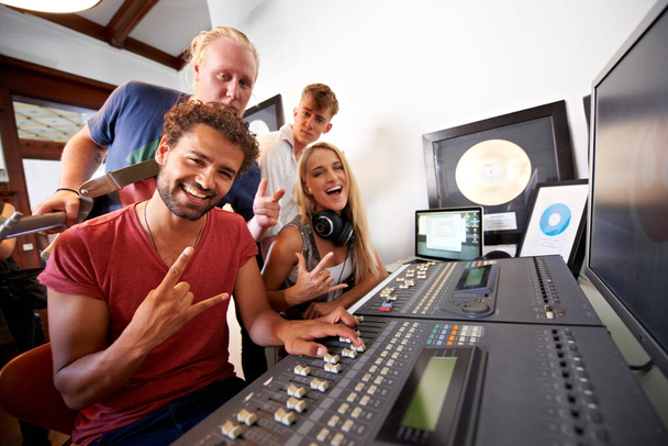 Hit Squad. Vier junge Musikproduzenten sitzen vor einem Mischpult in ihrem Studio - Porträt - Foto, Bild