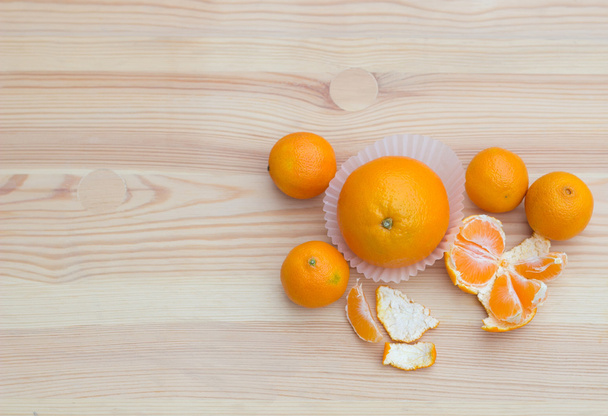 Orangen in Papierkörbchen auf hölzerner Textur mit Mandarinen - Foto, Bild
