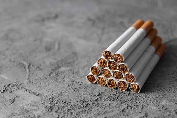 Concepto de daño del tabaquismo, cigarrillos sobre fondo texturizado gris - Foto, Imagen