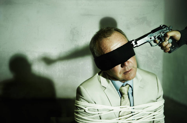 Страх перед дулом пистолета. Завязанный глазами бизнесмен с пистолетом у головы рядом с копирайтом - Фото, изображение