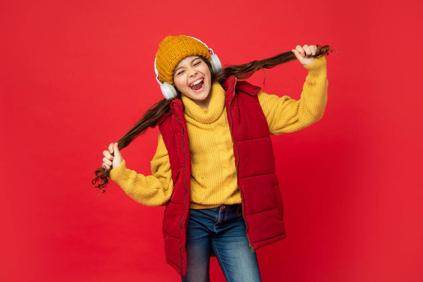 shouting kid in hat listen music in earphones holding hair, fun. - Photo, Image