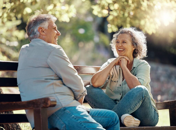 Park bench, couple and senior people with love and happiness in nature enjoying summer. Happy smile of elderly woman and man retirement together relax laughing outdoor having a fun conversation. - Photo, Image