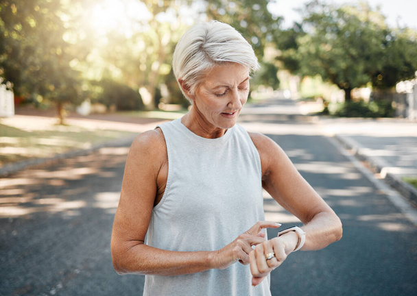 Fitness runner or senior woman with smartwatch check exercise results, process or goal for healthy, wellness lifestyle. Elderly sports person on digital technology typing workout steps or data on arm. - Foto, Imagem
