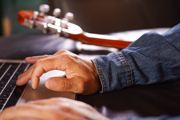 Mãos de homem procurando informações sobre como aprender a tocar guitarra online - Foto, Imagem