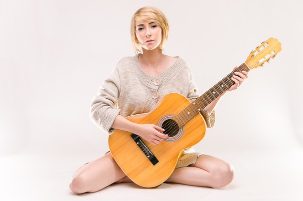 Joven hermosa dama rubia sonriente en suéter gris tocando la guitarra acústica
 - Foto, imagen