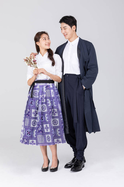 Korean young couple, man and woman wearing modern Hanbok, holding a bunch of flower - Foto, Bild