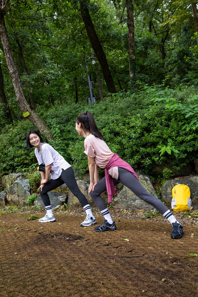 two Korean Asian female friends in 20s hiking and plogging in mountain__warm up - Foto, immagini