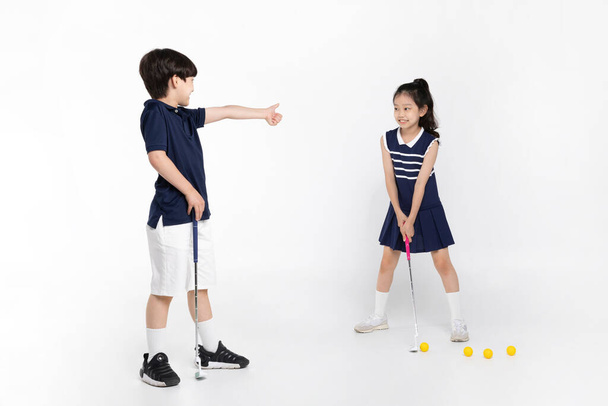 Korean boy and girl_fitness and exercise concept in white background__swinging golf club - Fotó, kép