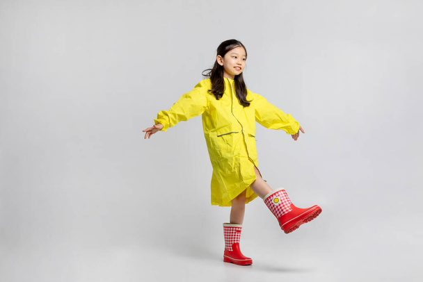 cute young Korean girl, rainy season concept in white background studio, walking forward in a raincoat - Photo, image