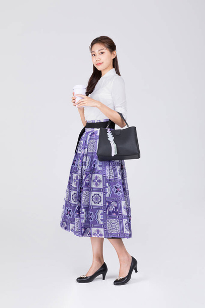 beautiful Korean woman in 20s wearing modern Hanbok, holding a bang and tumbler - Fotografie, Obrázek