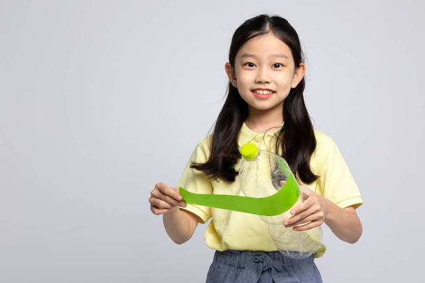 Korean young girl wearing gym clothes in white background studio, separation of plastic bottle label - Φωτογραφία, εικόνα