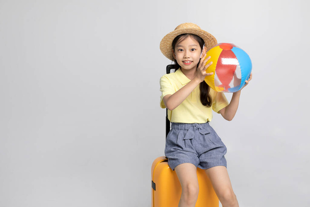 Korean young girl wearing gym clothes in white background studio, holding a beach ball sitting on the career - Photo, image