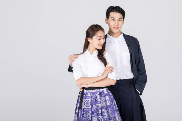Korean young couple, man and woman wearing modern Hanbok, putting arms around each other's shoulders - Fotó, kép