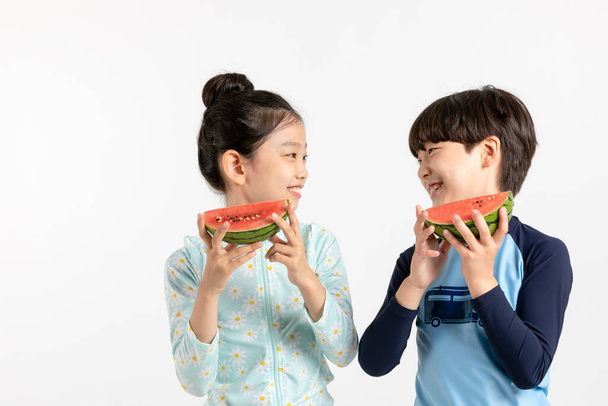 Korean boy and girl, summer concept in white background_holding watermelon - Photo, image