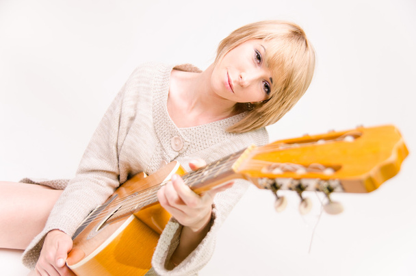 Joven hermosa sonriente señora rubia en suéter gris tocando la guitarra acústica
 - Foto, Imagen