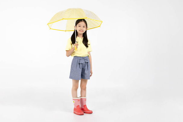 cute young Korean girl, rainy season concept in white background studio__wearing boots and an umbrella - Foto, immagini