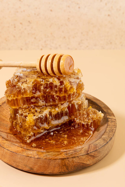 honey and honey dipper stick in a wooden bowl - Foto, afbeelding