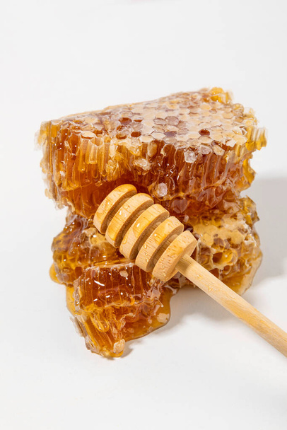 sliced honeycomb and honey dipper stick - Foto, afbeelding