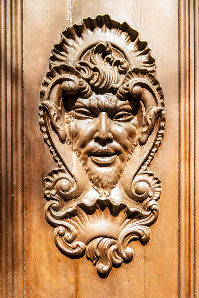 Porta in legno con incisione di un volto mitologico - Foto, immagini