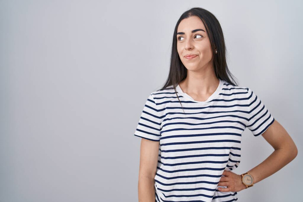 Mladá bruneta žena na sobě pruhované tričko s úsměvem dívá do strany a zírá pryč myšlení.  - Fotografie, Obrázek