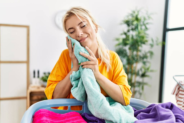 Young blonde girl smiling happy holding clean soft clothes at home. - Foto, Imagem
