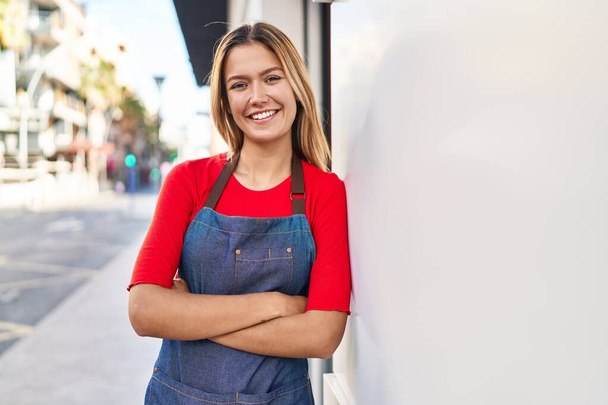 Young hispanic woman shop assistant standing with arms crossed gesture at street - Photo, Image
