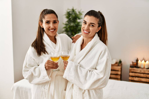 Две женщины в халате и шампанском стоят в салоне красоты - Фото, изображение
