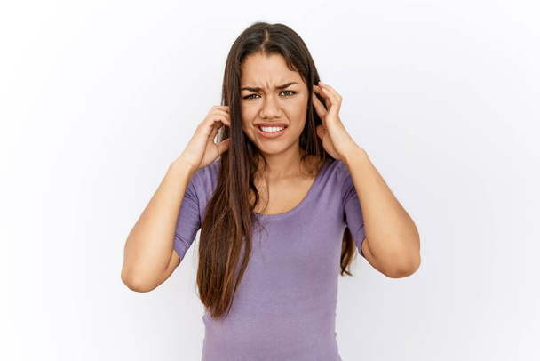 Fiatal barna nő áll elszigetelt háttér borító fülek ujjaival bosszús kifejezés a zaj a hangos zene. süket fogalom.  - Fotó, kép