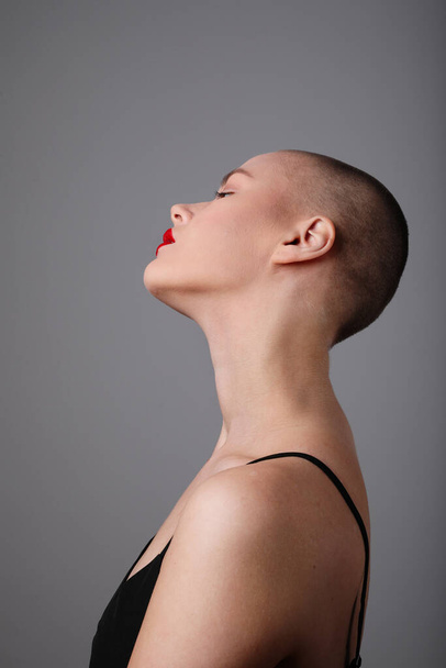 Side view of beautiful young bald woman posing over light grey background. High quality photo. - Φωτογραφία, εικόνα