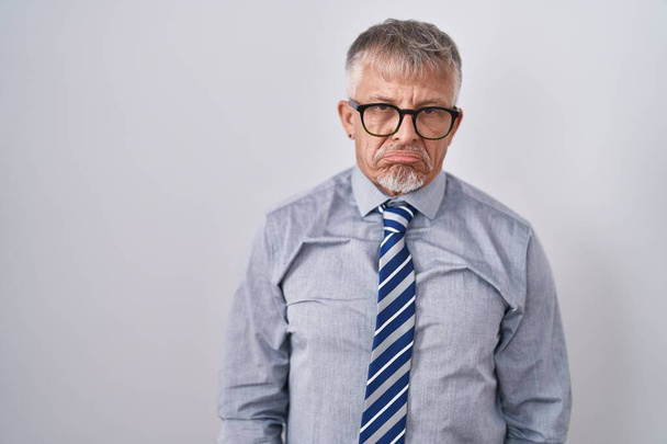 灰色の髪をしたヒスパニック系のビジネスマンは、眼鏡をかけて落ち込んで苦痛を心配し、怒って恐れて泣いています。悲しい表情.  - 写真・画像