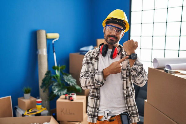 Nuori latinomies parta työskentelee kotona remontin kiire osoittaa katsella aikaa, kärsimättömyys, katsot kameraa rento ilme  - Valokuva, kuva