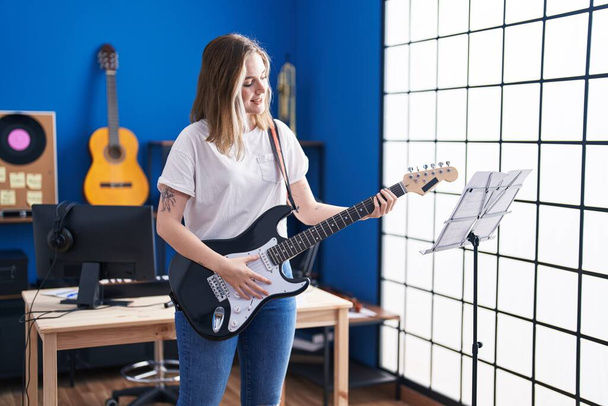 Young woman musician playing electrical guitar at music studio - Photo, Image